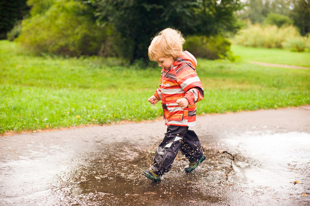 Boy running and jumping in puddles - 写真・画像