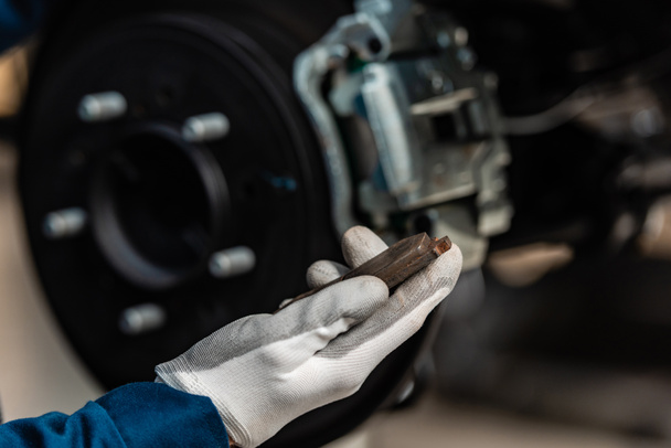 cropped view of mechanic holding brake pad near disc brakes - Φωτογραφία, εικόνα