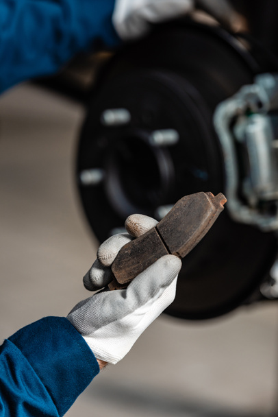cropped view of mechanic holding brake pad near assembled disc brakes - Photo, Image