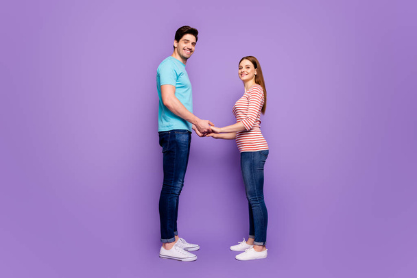 Will you marry me. Full body profile photo of cute couple stand opposite hold hands love confession wear casual blue striped t-shirts jeans isolated purple color background - Foto, Bild