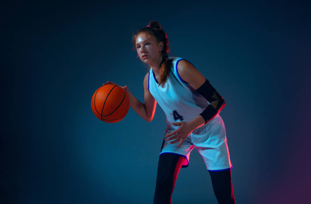 Молода біла баскетболістка на синьому фоні студії в неоновому світлі
 - Фото, зображення
