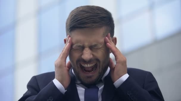 Man screaming from pain and massaging temples, sudden headache attack, spasm - Video, Çekim
