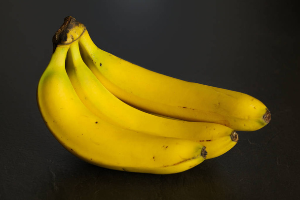 Bunch on bananas on black board / background. - Foto, Imagen