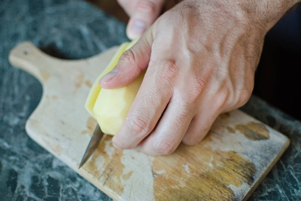 zbliżenie ręki krojącej ziemniaka nożem - Zdjęcie, obraz
