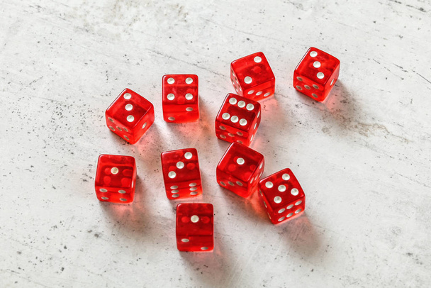 10 translucent red dices on white concrete board. - Zdjęcie, obraz