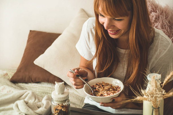 Healthy organic nutrition. Woman enjoying breakfast with oatmeal in bed, free space.  - Фото, изображение