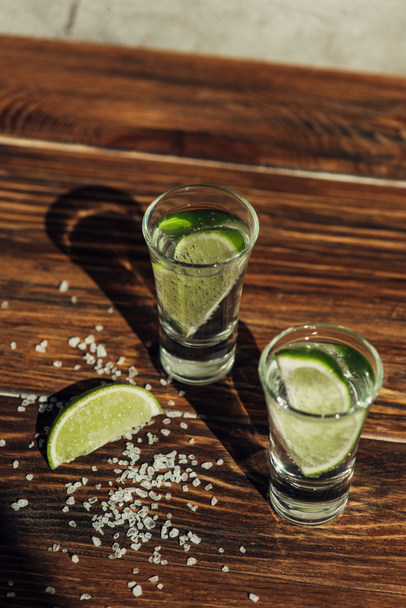 fresh tequila with lime and salt on wooden surface in sunlight - Photo, image