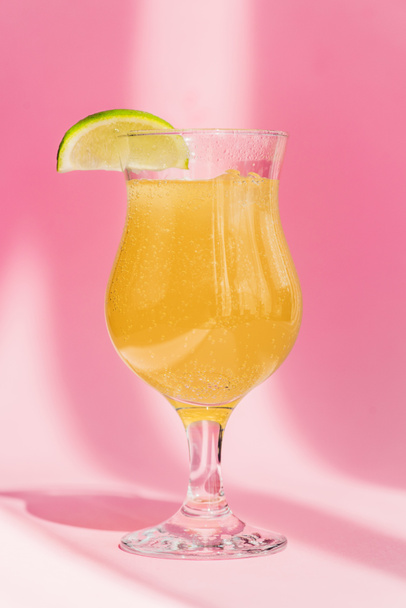 čerstvá žlutá limonáda s citrónem plátky na slunci na růžovém pozadí - Fotografie, Obrázek