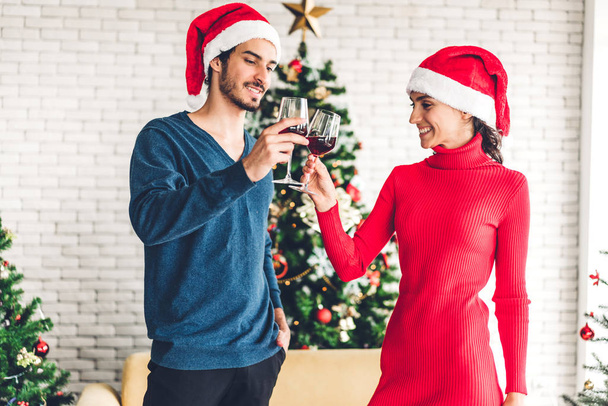 romantisches süßes Paar in Weihnachtsmannhüten, das Spaß hat und Wein trinkt - Foto, Bild