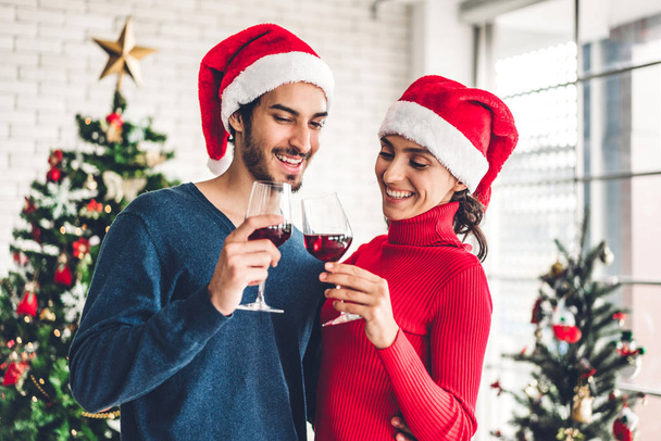サンタの帽子のロマンチックな甘いカップルはワインを楽しんで飲みます - 写真・画像