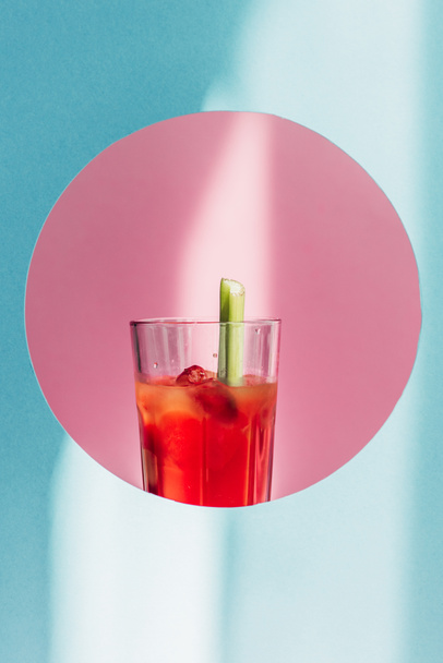 bloody Mary with celery in pink circle on blue background in sunlight - Photo, Image