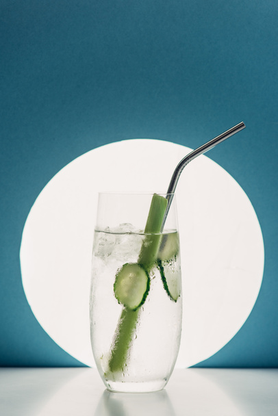 fresh lemonade with cucumber slices, celery and straw on blue background with back light - 写真・画像