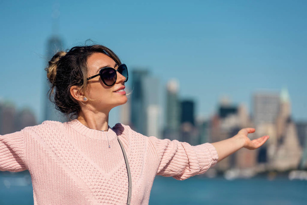 Kobieta w różowym swetrze pozuje na tle Nowego Jorku - Zdjęcie, obraz