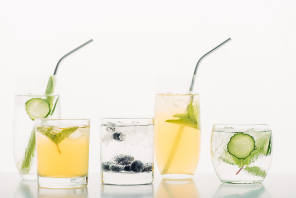 osvěžující nápoje s borůvkami, celerem, slámou, mátou, okurkou a ledem izolovanými na bílém - Fotografie, Obrázek