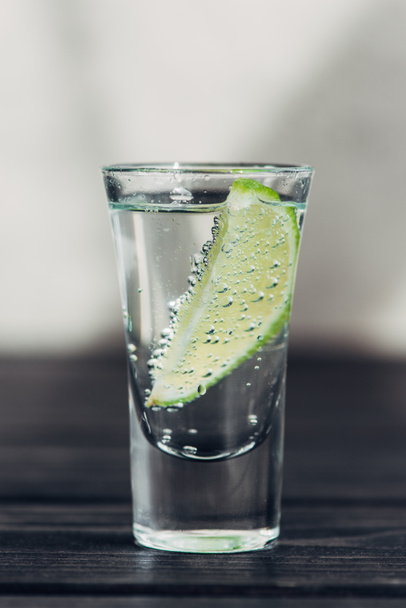 close up view of fresh tequila with lime on wooden surface - Photo, Image