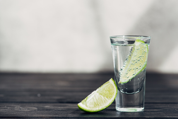 fresh tequila with lime on wooden surface - Foto, afbeelding