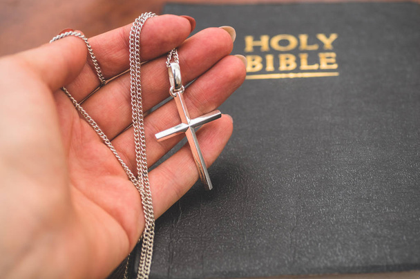 Mujer sosteniendo la cruz en la mano sobre el fondo de la Biblia
 - Foto, imagen