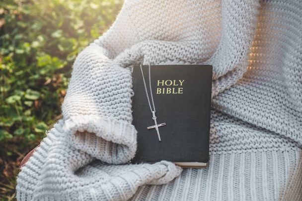 La Biblia y la cruz yacen en un suéter cálido. Concepto de fe, espiritualidad y religión
. - Foto, imagen