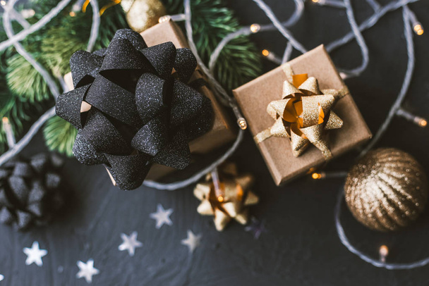Weihnachtsgeschenke auf schwarzem Hintergrund. Weihnachten Hintergrund mit Tanne, Girlanden, Geschenke. - Foto, Bild