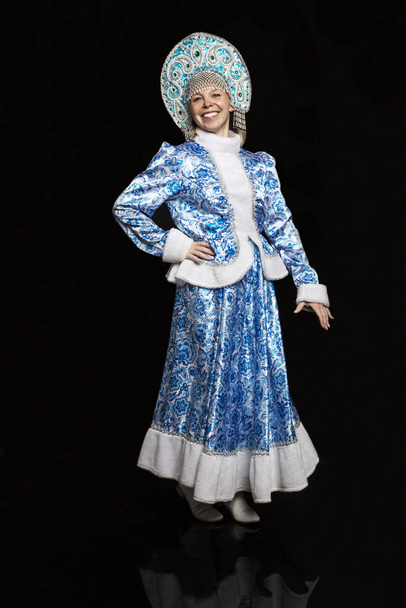 Χαμογελαστή γυναίκα με ένα όμορφο κοστούμι της Ρωσίδας καμαριέρας του χιονιού. Τη διάθεση της Πρωτοχρονιάς. Μαύρο φόντο.  - Φωτογραφία, εικόνα