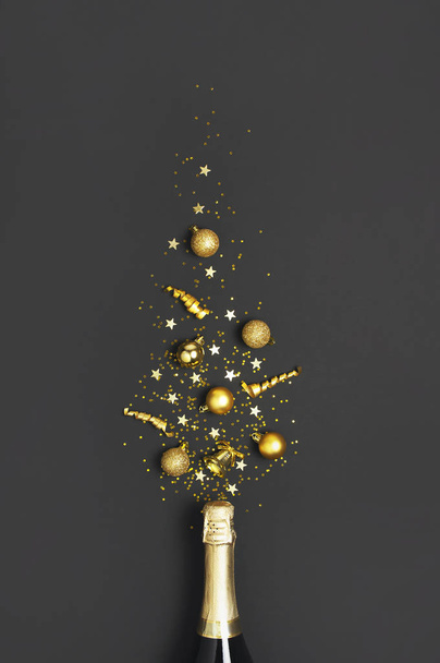 Christmas and New Year background. Champagne bottle, golden christmas balls, festive ribbons, star confetti on black background top view. Flat lay holiday card. Party concept Festive decorations 2020 - Photo, Image