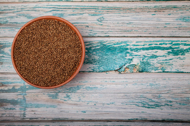 Raw buckwheat in a clay cup on a blue wooden background. Copy spaes. horizontal - Photo, Image