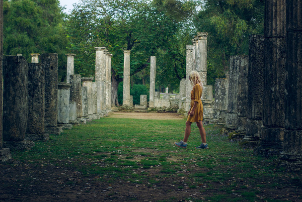 tyttö kävely Unescon perintö matkailukohde alueella Peloponnesoksen niemimaalla Kreikka puisto ulkona ympäristö antiikki sarakkeet arkkitehtuuri esineitä
 - Valokuva, kuva