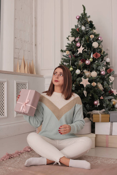 Christmas portrait of a beautiful woman with brown hair in a playful mood home style in a bright interior - Foto, imagen