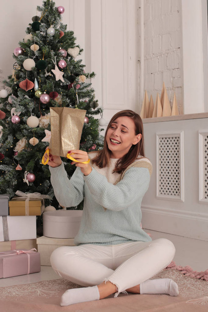 Weihnachtsporträt einer schönen Frau mit braunen Haaren in verspielter Stimmung in einem hellen Interieur - Foto, Bild