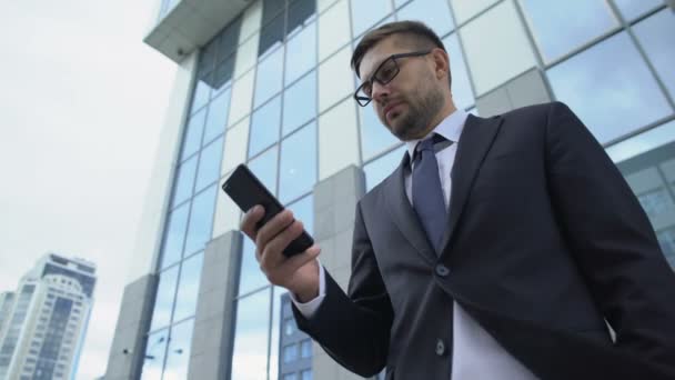 Businessman checking messenger using cellphone outdoors, communication apps - Кадры, видео