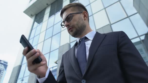 Frustrated man in suit reading bad news on phone, business failure, bankruptcy - Video