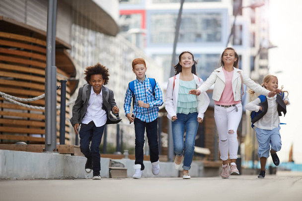 Iskola után az utcán együtt futó többnemzetiségű iskolások csoportja - Fotó, kép