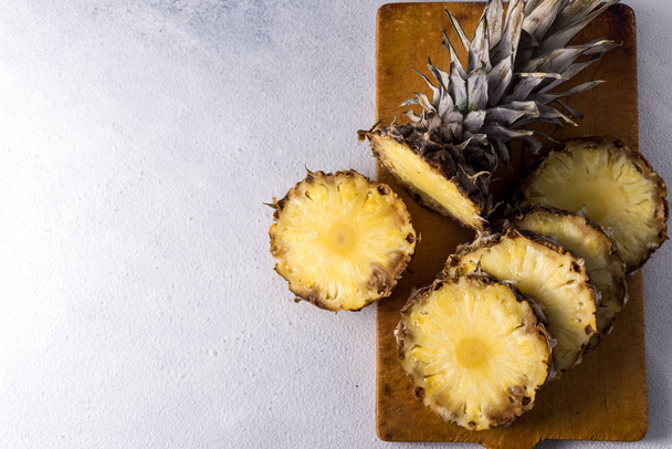 Ananas na pozadí dřevěné textury. Celý a nakrájený tropický ananas na dřevěnou desku. Horní pohled s místem pro text. - Fotografie, Obrázek