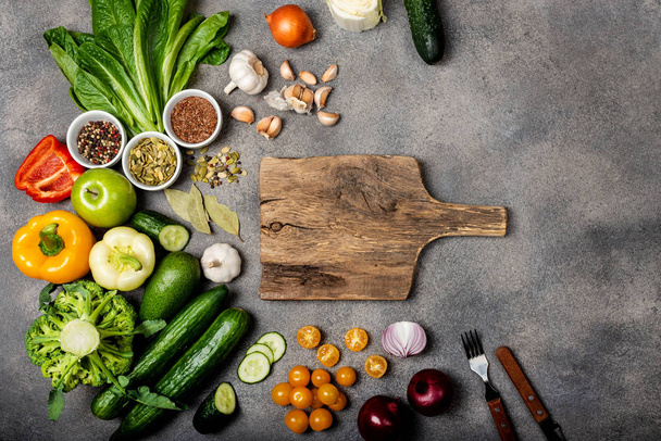 Složení se složkami pro přípravu zdravé vegetariánské stravy. Různá zelenina a koření a dřevěná deska na šedém pozadí. Dietní koncept. Horní pohled - Fotografie, Obrázek
