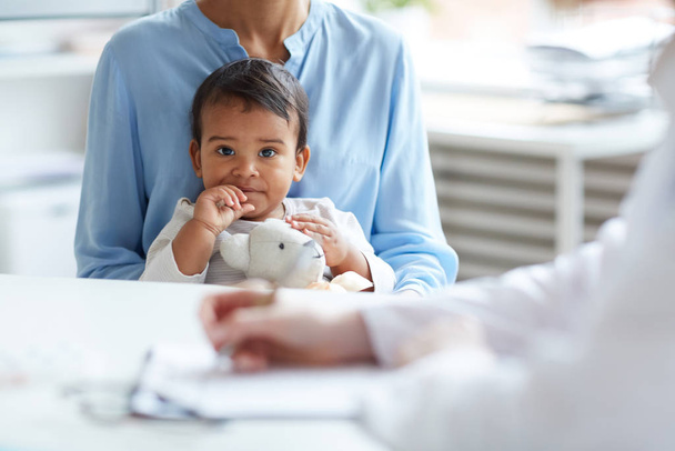 carino africano baby holding giocattolo seduta insieme con madre a medico ufficio - Foto, immagini