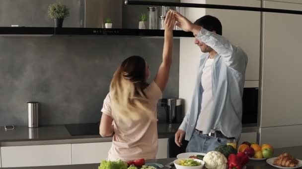 Happy young couple dancing in kitchen. Caucasian family in casual clothes having fun dance together, enjoying happy morning, romantic relationship at home. Slow motion - Metraje, vídeo
