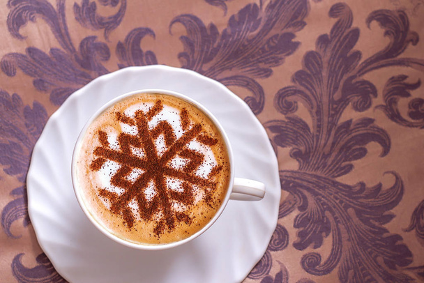 Cappuccino con un modello di fiocchi di neve da cannella su schiuma di latte durante le vacanze di Natale
 - Foto, immagini