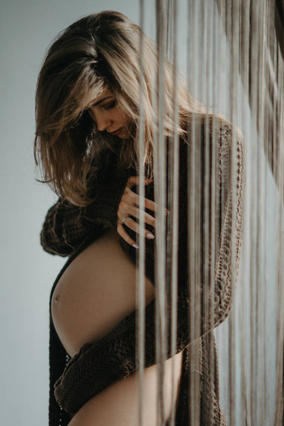 Mujer embarazada se pone de pie y abraza su barriga
. - Foto, imagen