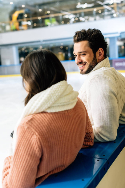 χαρούμενο ζευγάρι με πουλόβερ που περνάει χρόνο στο παγοδρόμιο   - Φωτογραφία, εικόνα