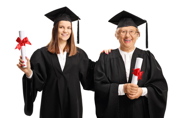 Young and senior female graduates holding diplomas - Foto, afbeelding