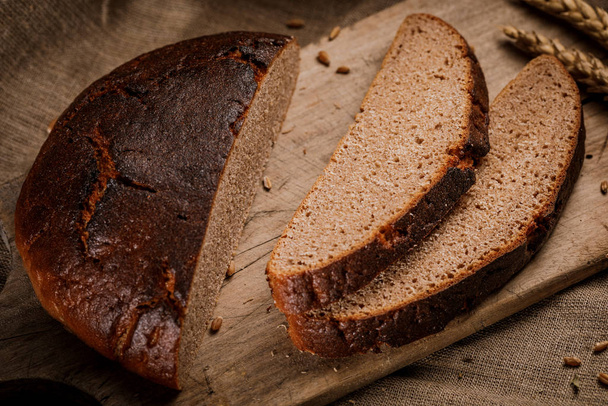 Freshly baked bread cut into chunks on a wooden Board - Фото, зображення