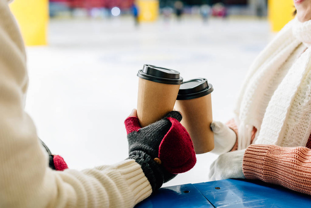 cropped view of couple holding paper cups of coffee to go on skating rink - Foto, Imagen