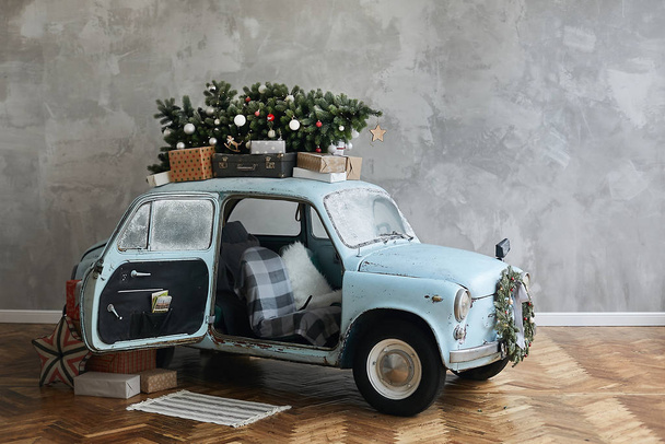 Christmas decorated classic car. A vintage car decorated for New year holidays loaded with festive gifts. Christmas retro car decorated loaded with Christmas tree and presents - Фото, изображение