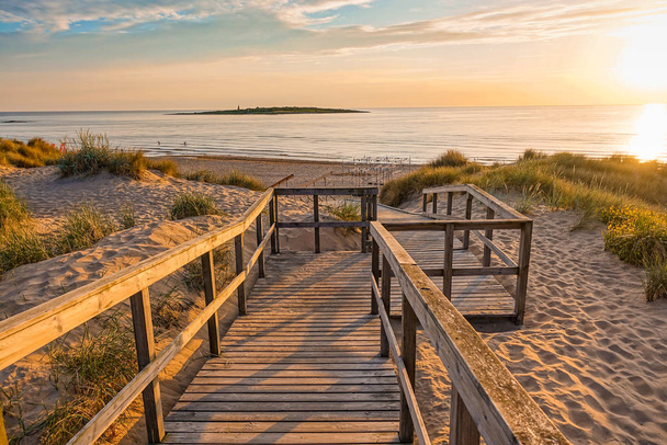 Wooden path at Baltic sea over sand dunes with ocean view, sunset summer evening - Photo, Image