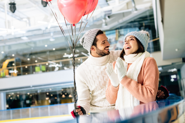 pareja emocionada con globos rojos en forma de corazón que pasan tiempo en la pista de patinaje en el día de San Valentín
 - Foto, Imagen