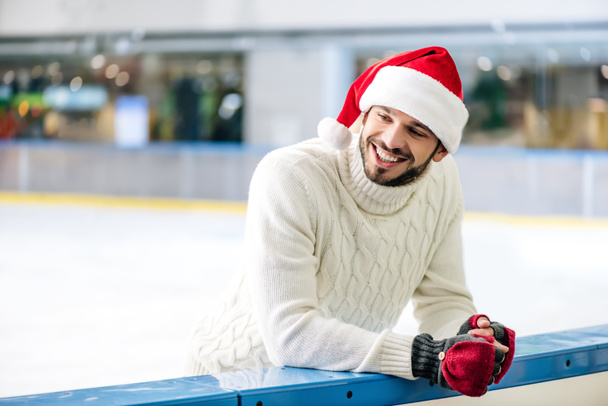 happy man in sweater and santa hat on skating rink - Fotoğraf, Görsel