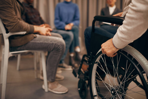 Közelkép a kerekesszékben ülő idős fogyatékkal élő emberről és a látogató üzleti találkozóról - Fotó, kép