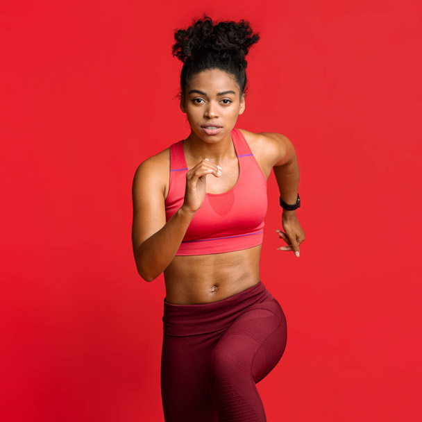 Portret van draaiend Afrikaans fitness model over rood - Foto, afbeelding