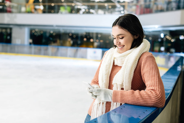 beautiful happy girl using smartphone on skating rink - Fotó, kép