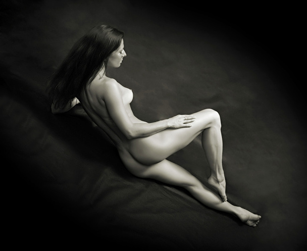 Monochrome shot of a naked beautiful woman posing on a black background. - Foto, imagen